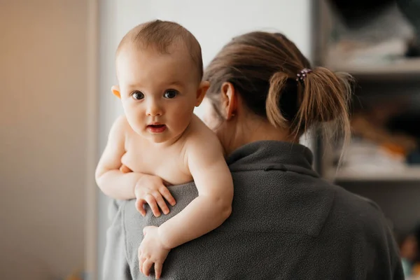 Annenin kucağında bebek varken çekilmiş bir ev fotoğrafı. Anne 5 aylık kızına sarılıyor. Sevgi dolu bir anne yeni doğmuş bebeğini taşıyor. Boşluğu kopyala