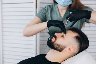 Mezoterapi prosedürü. Bir kozmetik uzmanı genç bir adamın kafasına mezoterapi uygular. Kılların güçlenmesi ve büyümesi.