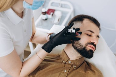 Sakallı şık bir adam estetik kliniğe gidip dudak dolgusu yaptırıyor, yakın plan çekiyor. Çekici Adam erkek spa salonunda güzellik iğnesi yaptırıyor. Erkekler için yaşlanma karşıtı tedavi