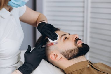 Erkekler için dudak büyüklüğü arttı. Genç, şık sakallı bir kadının dudaklarına hyuleronik asit enjekte edildi.