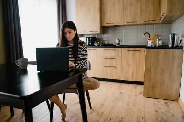 Junge Freiberuflerinnen Hauskleidung Arbeiten Laptop Und Sitzen Tisch Der Küche — Stockfoto