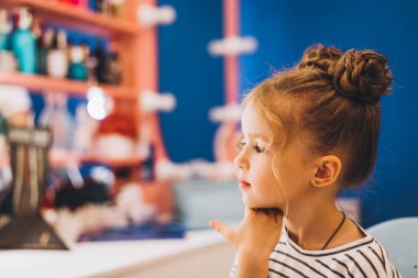 Güzel bir saç stili yaptığı çocuklar için bir güzellik salonunda şık küçük bir kız. Kadın stilisti küçük kıza şık saç stili yapar..