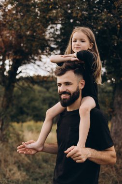 portrait of father and child. A stylish father with a beard keeps on his arms a child, a little girl, they embrace and smile, rejoice and have fun. Happy Father's Day