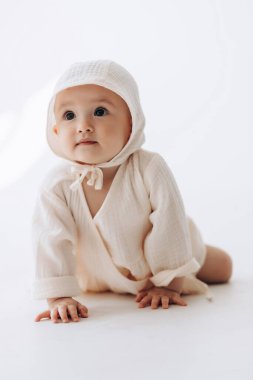 Sürünmeye başlamış küçük bir bebeğin şirin stüdyo portresi. Çocuk ilk adımlarında güler ve sevinir.