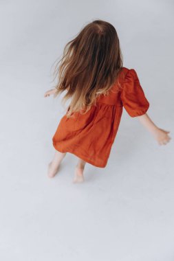 4 yaşında güzel bir kız koşuyor, eğleniyor, zıplıyor ve gülüyor.