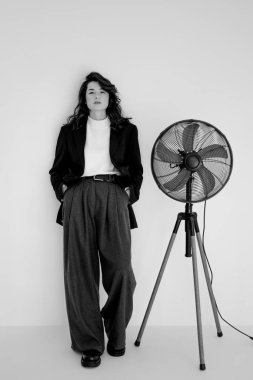 Geniş pantolon ve ceket giyen genç bir kadının siyah beyaz portresi.