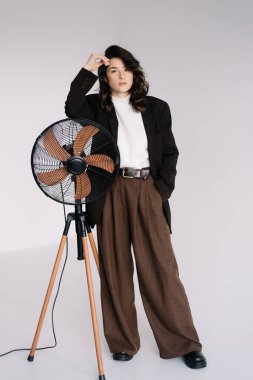 Çekici kadın iş kıyafeti giyer. Esmer manken beyaz gömlek, siyah erkek ceketi ve kahverengi bol pantolon giyer. Kış, sonbahar ya da bahar minimum giysi.