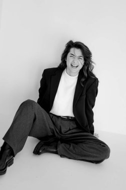 Geniş pantolon ve ceket giyen genç bir kadının siyah beyaz portresi.