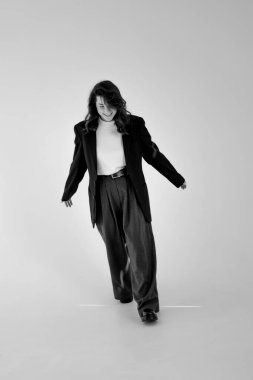 Geniş pantolon ve ceket giyen genç bir kadının siyah beyaz portresi.