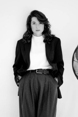 Geniş pantolon ve ceket giyen genç bir kadının siyah beyaz portresi.