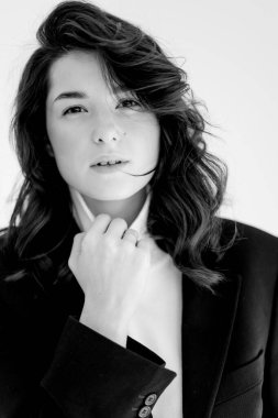 Geniş pantolon ve ceket giyen genç bir kadının siyah beyaz portresi.