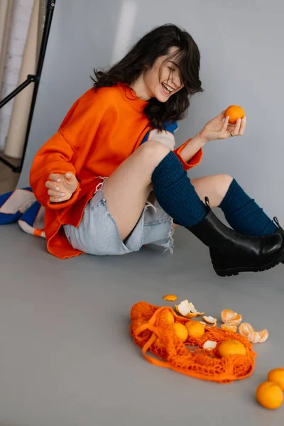 Mladá Dívka Sedí Podlaze Fotostudiu Mandarinkami Rukou Pózuje Pro Fotografii — Stock fotografie