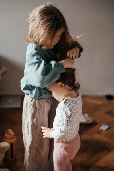 Starsza Siostra Przywiązuje Kucyk Głowy Młodszej Siostry Układa Włosy Troszczy — Zdjęcie stockowe