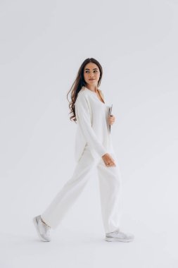 29.04.22 Kyiv, Ukrayna: Beyaz arka plan stüdyo siklonunda fotoğraf için poz veren genç bir kadının şık portresi. Pantolon giydirilmiş doğal gün ışığı.