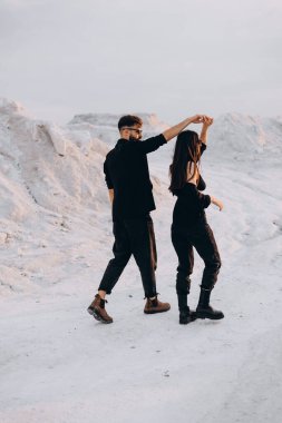 Beyaz dağların arka planında yürüyen ve sarılan şık bir çift. Hoş hippi çift birlikte eğleniyor. Gençlik, aşk ve yaşam tarzı kavramı. İlkbahar.