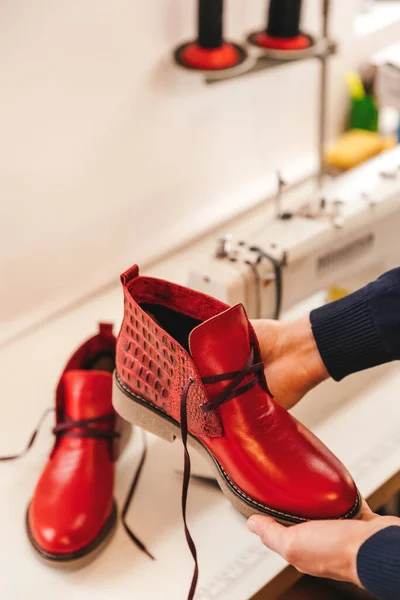 A pair of finished leather shoes in the hands of a master.