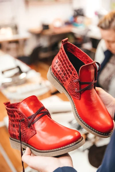 A pair of finished leather shoes in the hands of a master.