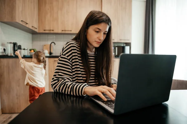 Serbest çalışan kadın, mutfak ofisindeki masanın başında oturup dizüstü bilgisayarla çalışıyor. Oyuncu çocuk dikkatini işten uzaklaştırıyor, çocuk gürültü yapıyor ve meşgul annesinden ilgi istiyor.
