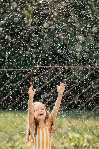 暑い夏の日に雨のように降ってくる水に笑顔の女の子が幸せ — ストック写真