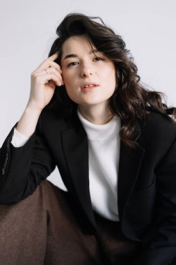 Çekici kadın iş kıyafeti giyer. Esmer manken beyaz gömlek, siyah erkek ceketi ve kahverengi bol pantolon giyer. Kış, sonbahar ya da bahar minimum giysi.