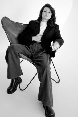 Geniş pantolon ve ceket giyen genç bir kadının siyah beyaz portresi.