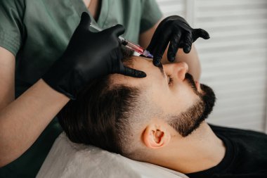 Mesotherapy. Injections with vitamins for hair growth on bald parts of the head in a young man