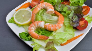 Sağlıklı sebze ve taze domatesli karides salatası, marul, tabakta havuç. Diyet menüsü.