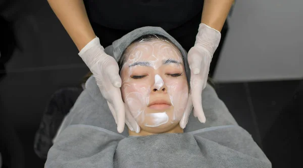 A beautiful Asian woman undergoes facial rejuvenation in a beauty clinic using modern medical equipment. By certified beauty experts according to standards.