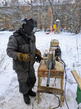 Bir adam kışın sokakta metal bir yapı yapıyor.