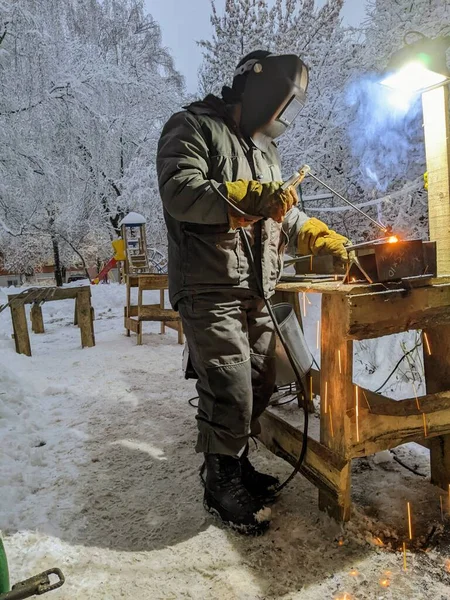 Elektrikli kaynakçı kışın çalışır. Kışın metalle çalışmak. Bir adam metal kaynıyor..