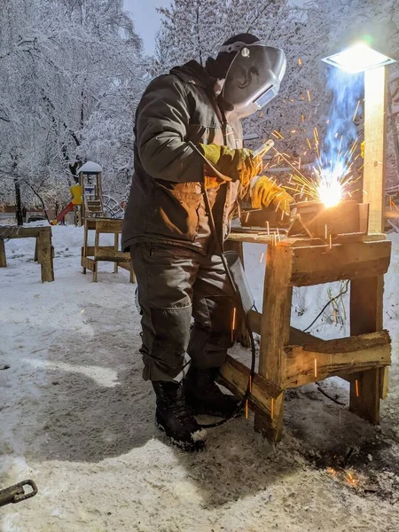 Elektrikli kaynakçı kışın çalışır. Kışın metalle çalışmak. Bir adam metal kaynıyor..