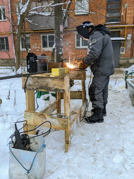 Bir adam kışın sokakta metal bir yapı yapıyor.