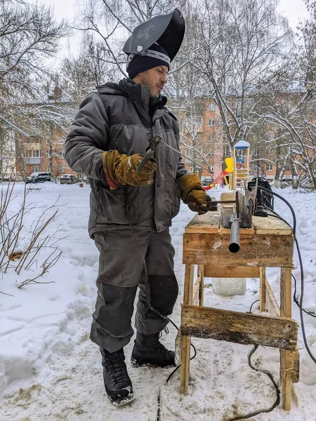 Elektrikli kaynakçı kışın çalışır. Kışın metalle çalışmak. Bir adam metal kaynıyor..
