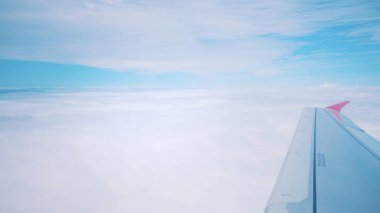 Kanatlarda, bulutlarda ve gökyüzünde halihazırda yüksek irtifada olan bir uçağın görüntüsü.