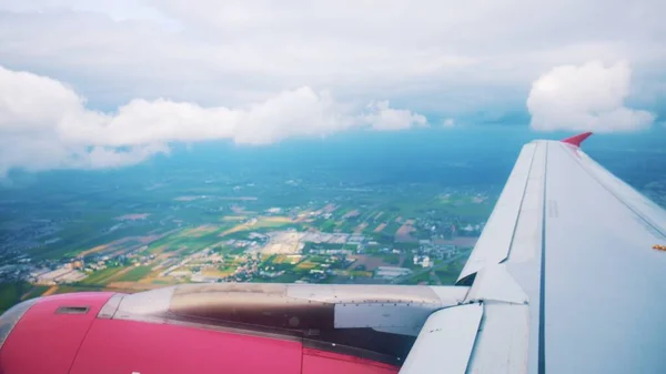 View from the plane on the wings of the plane, the pink engine, the clouds and the inhabited ground — Stock Photo, Image