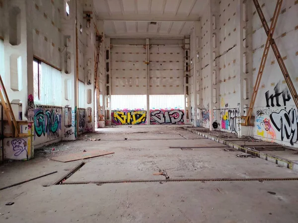 Grande armazém vazio abandonado assinaturas interiores na parede usando tinta spray — Fotografia de Stock