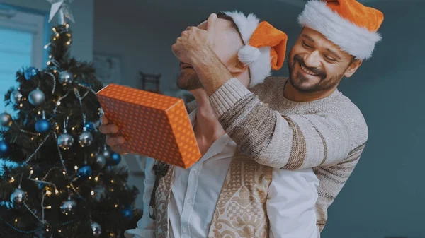 Νεαρό αντρικό ζευγάρι να δίνει δώρα ο ένας στον άλλο με χριστουγεννιάτικες κάλτσες. Ομοφυλοφιλική σχέση και χειμερινές διακοπές έννοια — Φωτογραφία Αρχείου