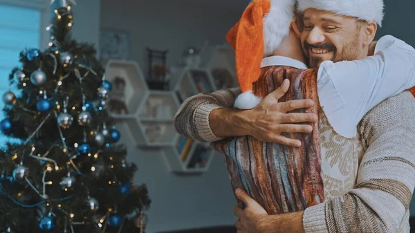 Νεαρό γκέι αντρικό ζευγάρι αγκαλιάζεται μπροστά στο χριστουγεννιάτικο δέντρο — Φωτογραφία Αρχείου