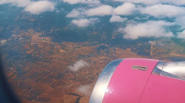 View from the plane of a pink engine in the height of the clouds on the ground where you can see a beautiful panorama — Stock Photo, Image
