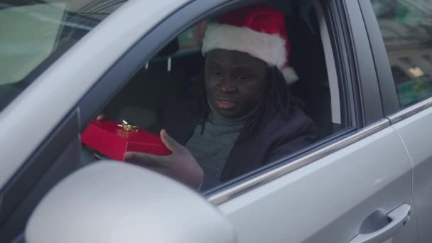 Похмурий афроамериканець дарує христам у вікно свого автомобіля. — стокове відео