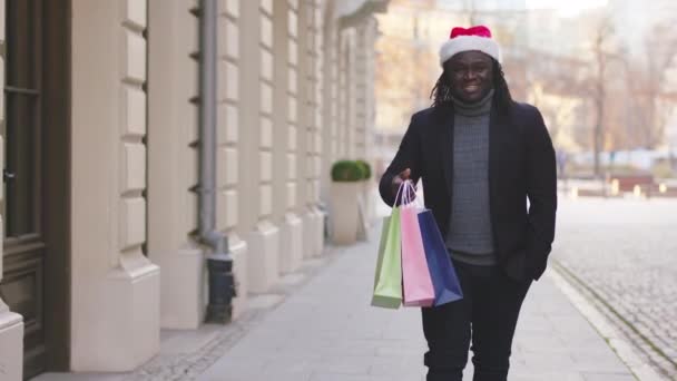 圣诞购物。身穿西服的非裔美国黑人拿着装有圣诞礼物的彩包 — 图库视频影像