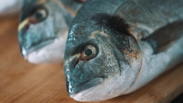 Pesce Dorado fresco su un tagliere di legno - Primo piano Vista della testa e degli occhi di pesce — Video Stock