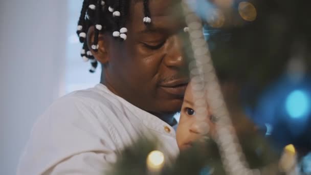 Negro afroamericano padre holding adorable mulato bebé cerca de el árbol de navidad — Vídeos de Stock