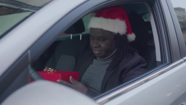 Knappe Afro-Amerikaanse man geeft een kerstcadeau door het raam van zijn auto — Stockvideo