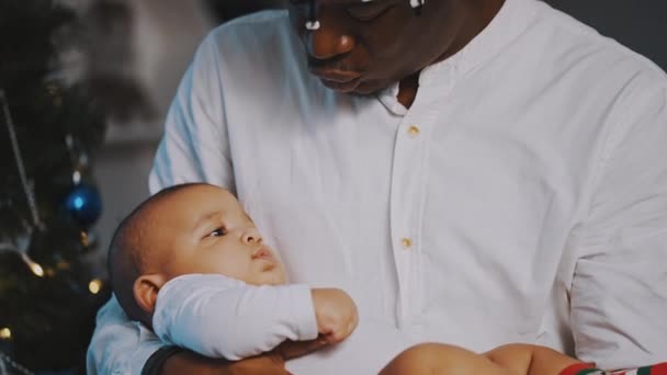 Afroamericano padre nero che tiene adorabile mulatto bambino vicino all'albero di Natale — Video Stock