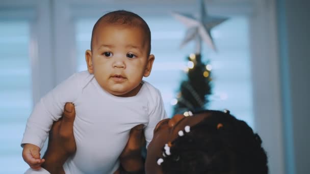 Baby first christmas. Papa und Neugeborenes spielen umgeben kaufen rote Geschenkboxen und Weihnachtsmütze — Stockvideo