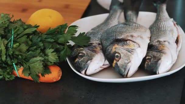 Dorado-Fisch wird auf einen weißen Teller gelegt, fertig zum Kochen mit frischem Gemüse — Stockvideo