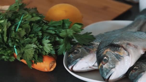 Świeża ryba jest umieszczony na białym płycie z sałatą Marchew i cytryna na stronie — Wideo stockowe