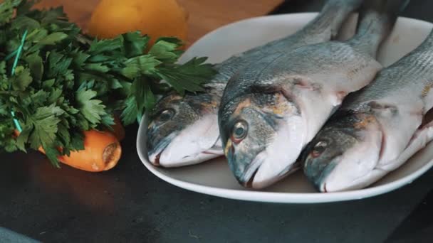 Świeże ryby Dorado jest umieszczony na białym talerzu gotowy do gotowania z warzywami — Wideo stockowe