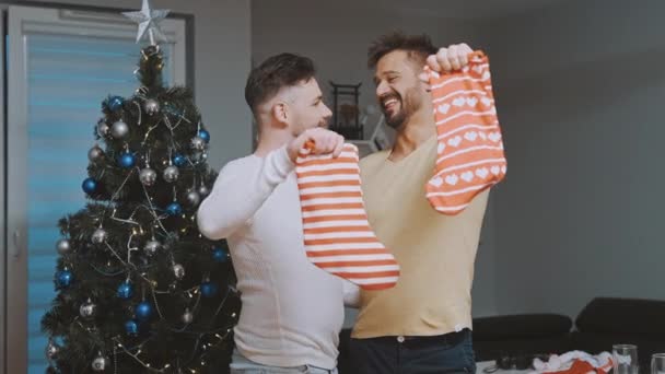 Милая гей-пара проверяет рождественские чулки на наличие подарков — стоковое видео